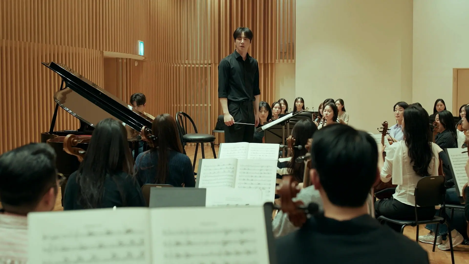 Jeong-yo faces the orchestra from the podium, baton in hand
