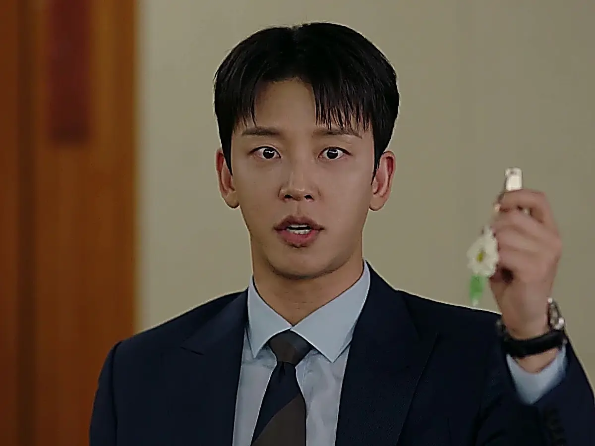 Cha Seok-jin presenting the recovered USB in a navy suit and light blue dress shirt