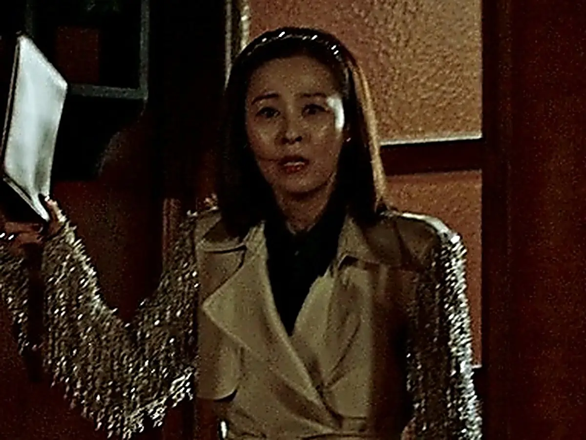 Woman holding a folder, wearing a trench coat with shimmering metallic fringe sleeves
