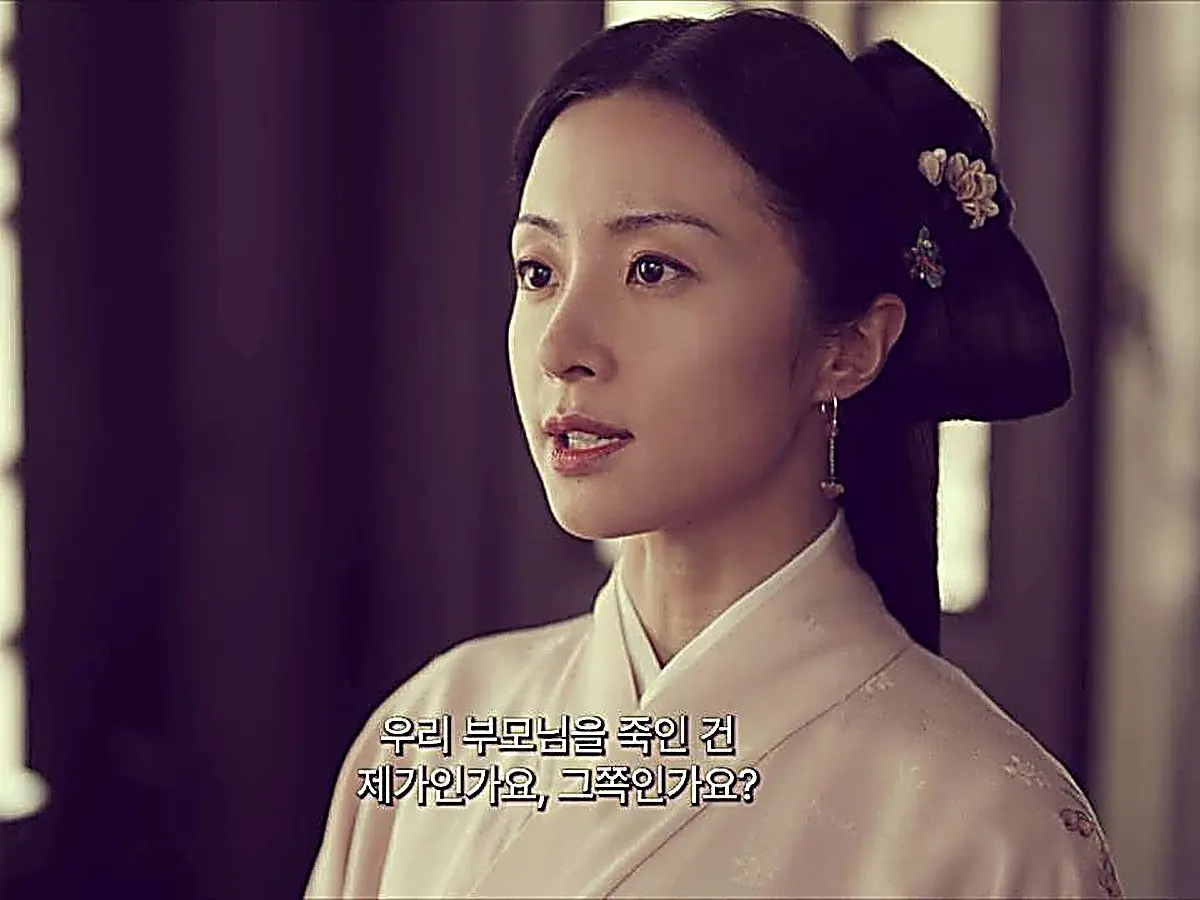 Portrait of a woman wearing a pale pink robe and dangling earring looking directly ahead