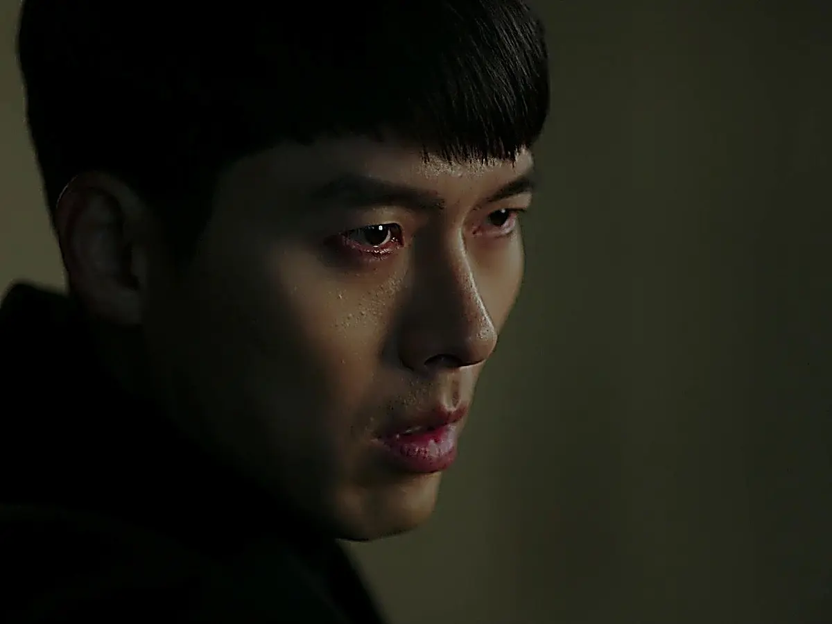 Close-up of a man in low light with short dark hair staring intently forward