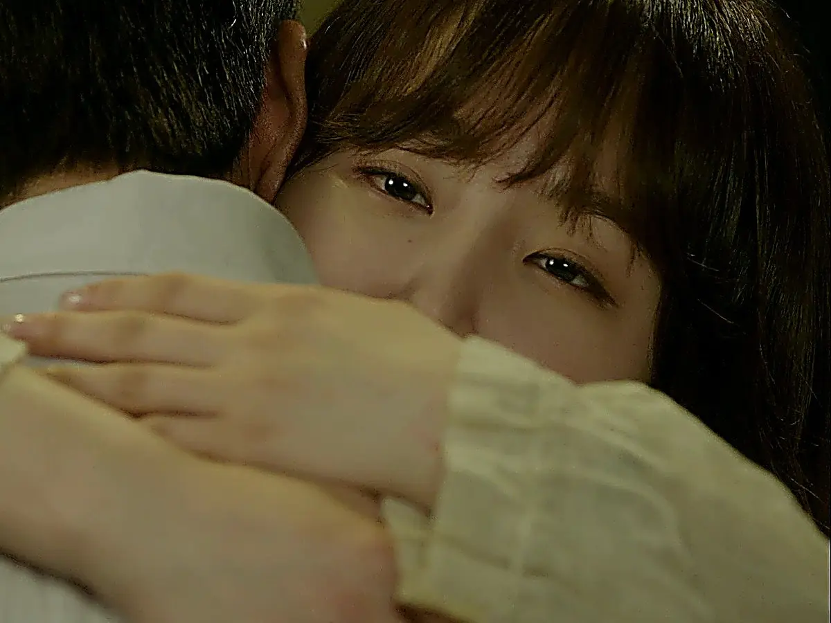 Close-up of a woman resting her face against someone's shoulder while embracing them