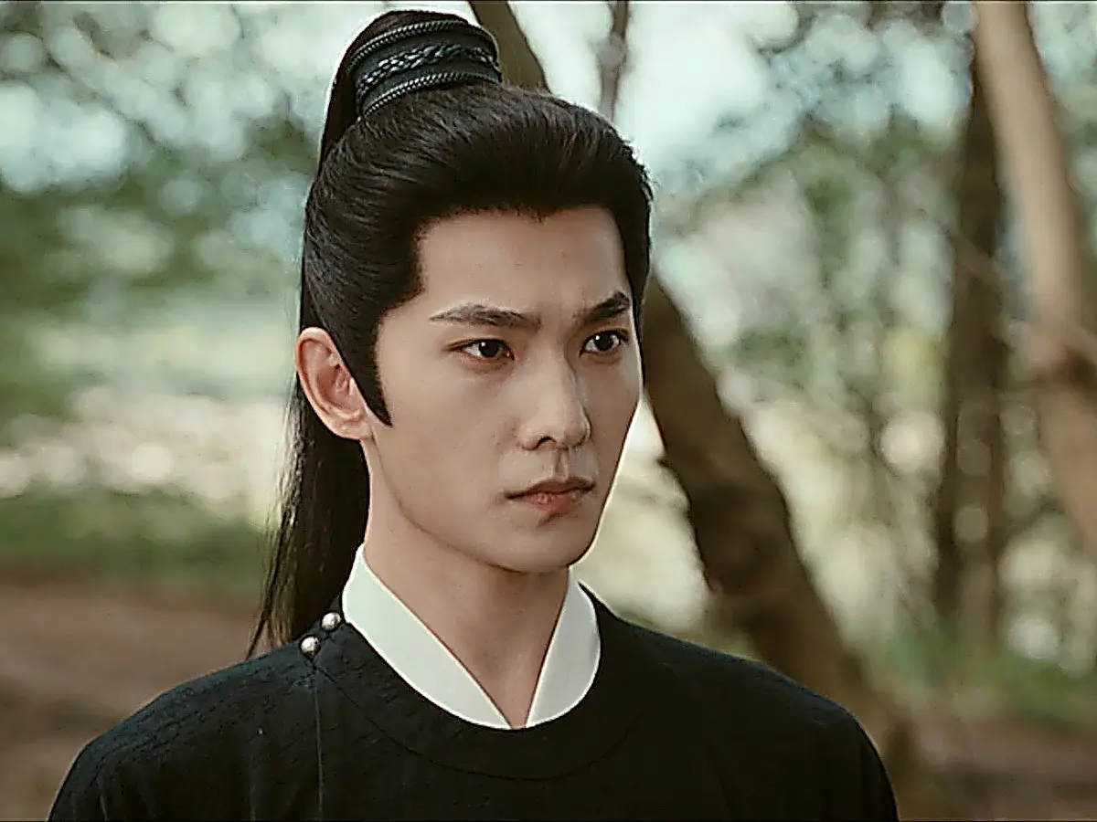 Zhan Zhao in a structured black travel coat with a high white inner collar and a high ponytail