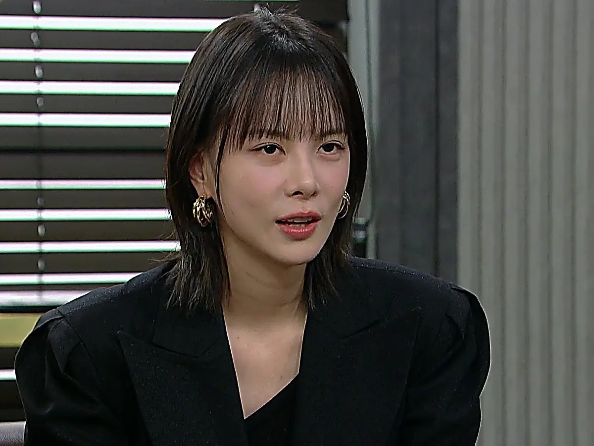 Kang Hae-ra wearing a black structured blazer with wide peaked lapels and gold hoop earrings