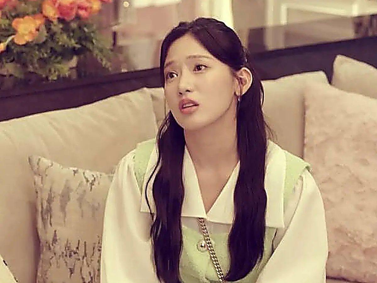 Cha Se-na sitting on a sofa wearing a mint vest over a crisp white pointed collar blouse
