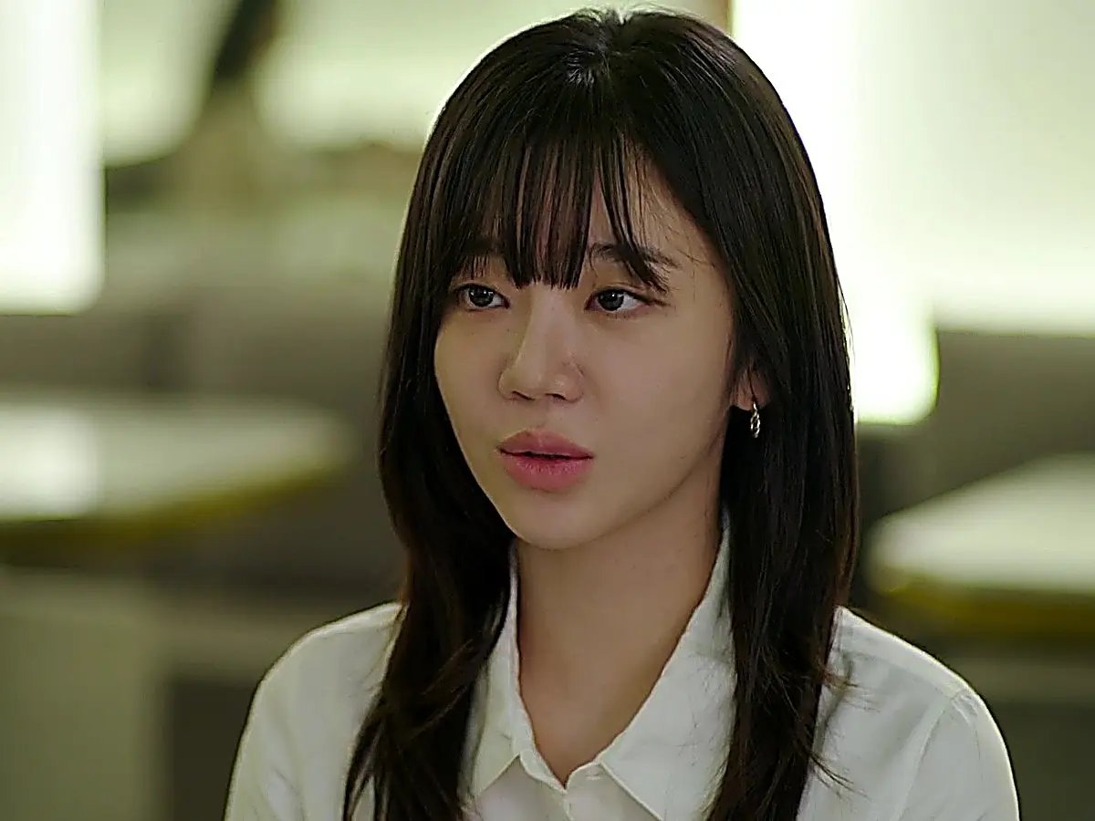 Go Eun-seol in a white button-down shirt with a pointed collar listening with a subtle expression