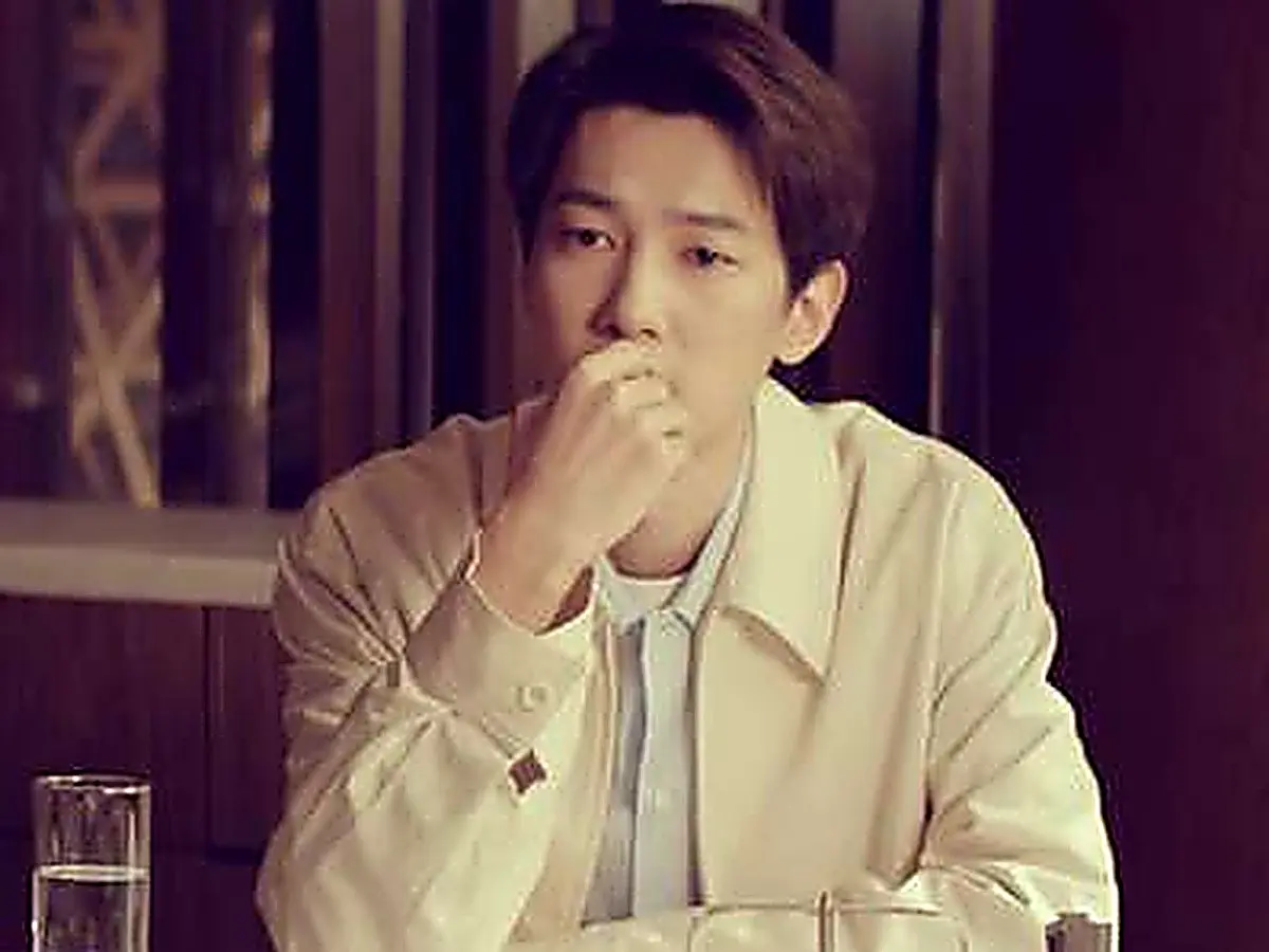Jiang Yubai seated wearing a light collared jacket over a blue button-down shirt
