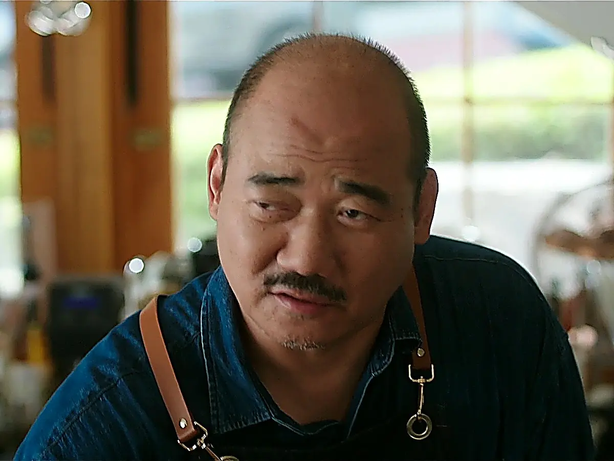 Cafe Owner Oh brewing coffee while reflecting on sudden wealth
