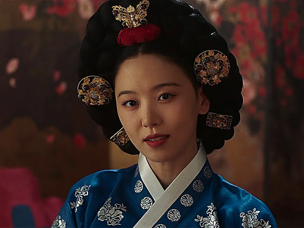 Consort Kang Mok-ju smiling coldly while adorning hair ornaments in front of her mirror