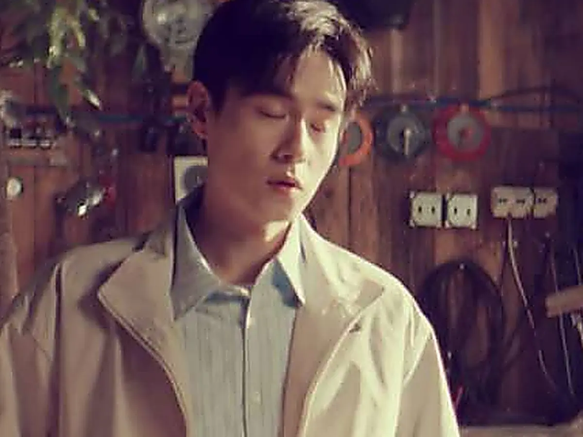 Jiang Yubai wearing a light zip-up jacket over a striped collared shirt indoors with his eyes closed