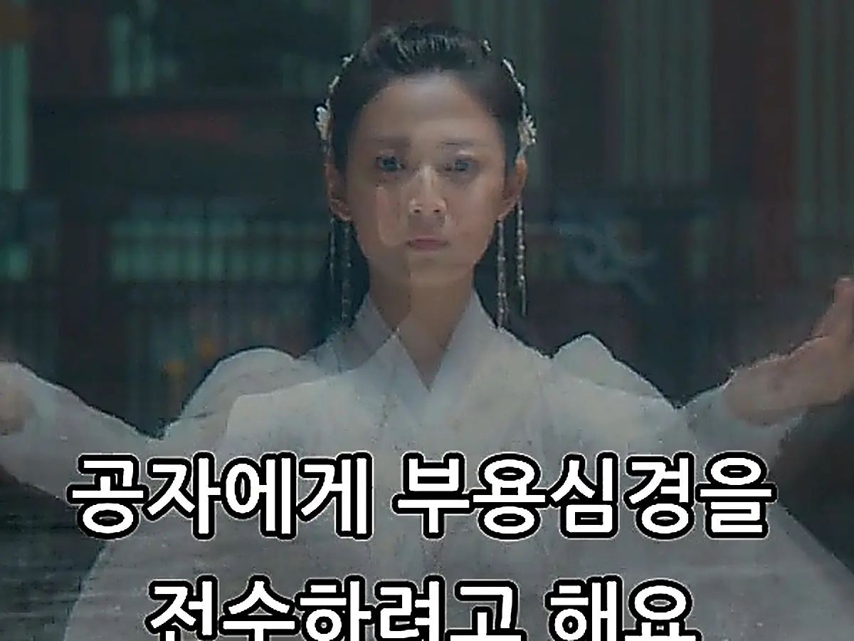 A woman wearing a white robe and floral hair ornaments, raising both arms outward in an upper-body shot