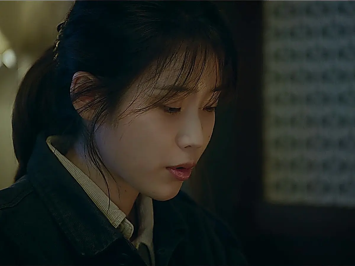 Lee Ji-an wearing a dark utility jacket and layered knit top