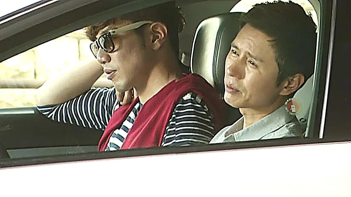 Choi Yoon wearing a casual grey polo shirt while seated in the car beside Lee Jung-rok