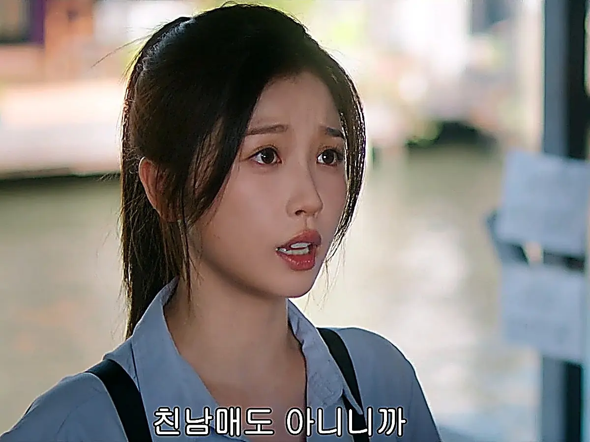 Jiang Mu in a ponytail and blue button-down shirt speaking with an earnest expression