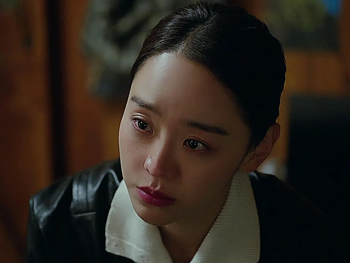 A woman with dark hair in a leather jacket and white collared shirt looking emotional with tears in her eyes
