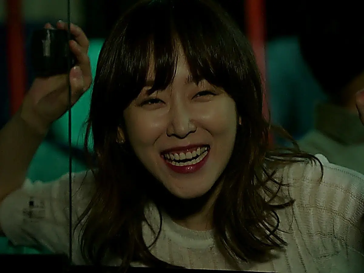 Oh Hae-young smiling out a bus window in a cream textured short-sleeve top