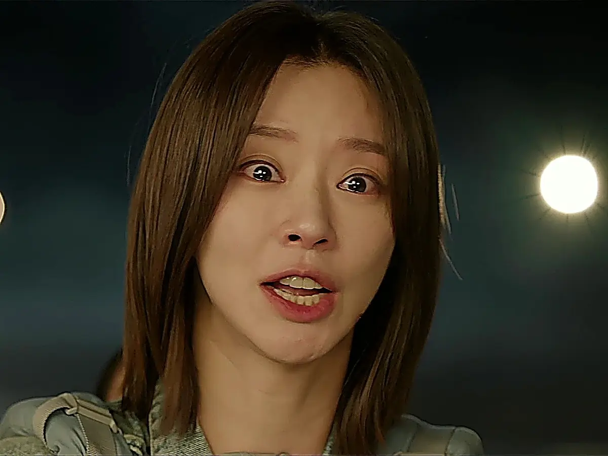 Woman with shoulder-length brown hair outdoors at night speaking with an anxious expression