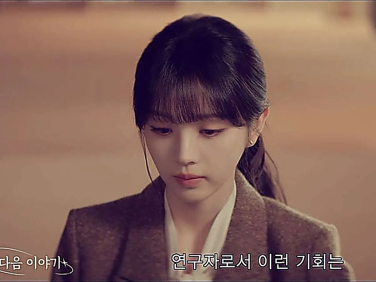 Lin Zhixia wearing a textured tailored blazer over an ivory collared shirt with hair in a low ponytail