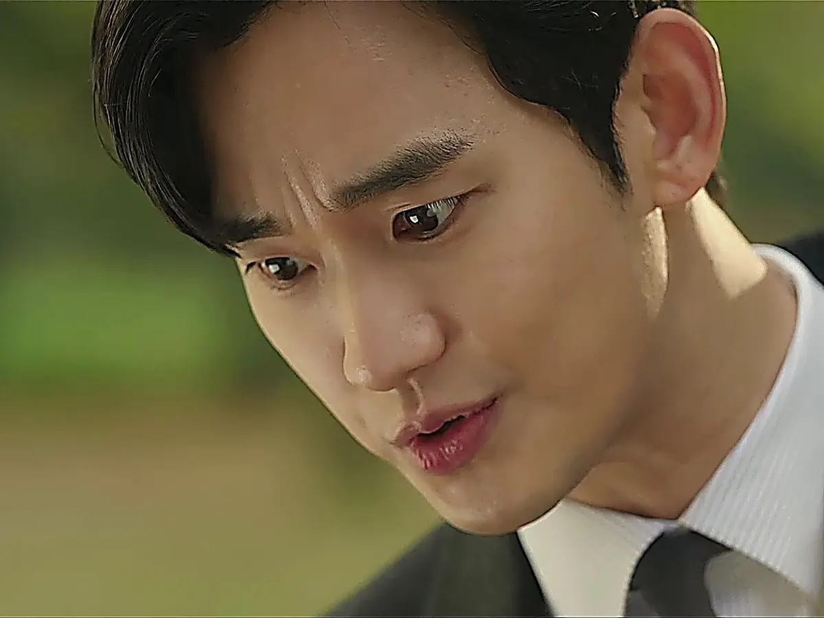 Close-up of a man in a suit looking downward with a focused, serious expression