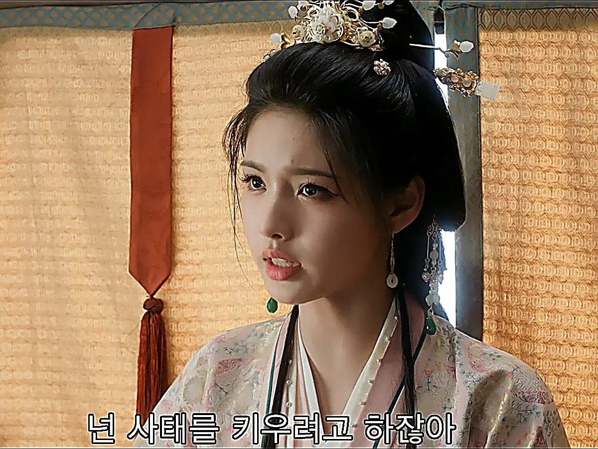 A woman in a light floral robe and dangling hair ornaments speaking inside a carriage