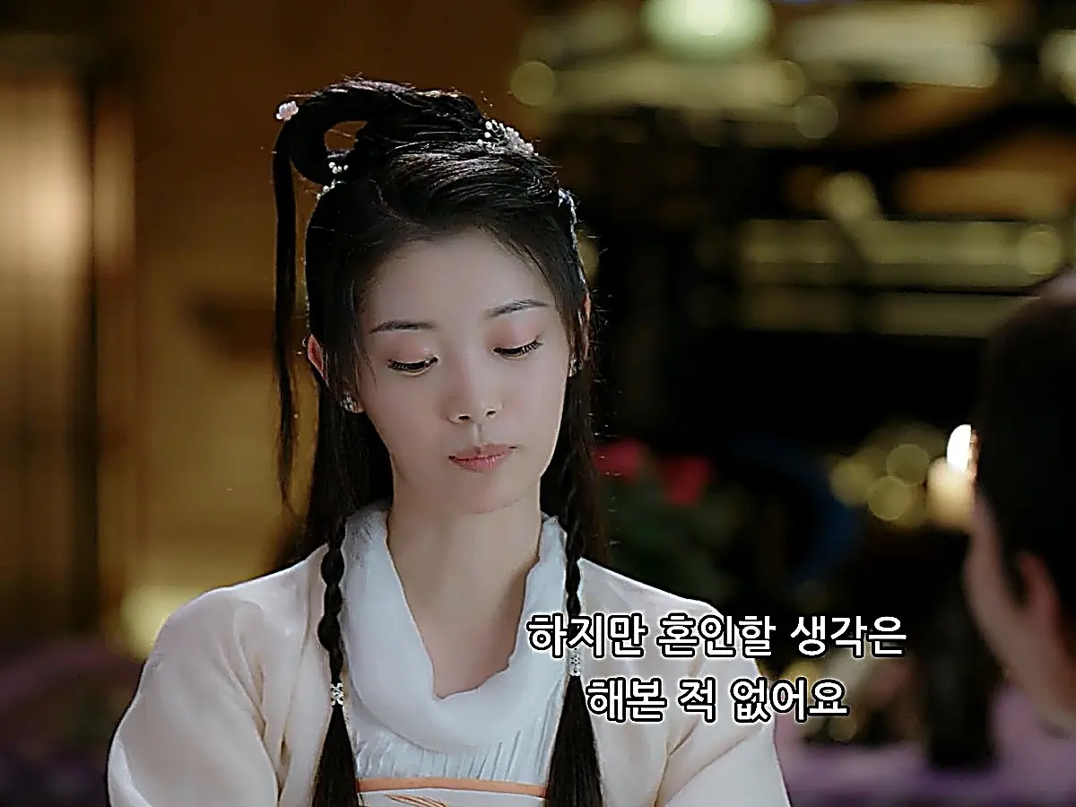 A woman with styled hair and silver floral pins gazing downward quietly