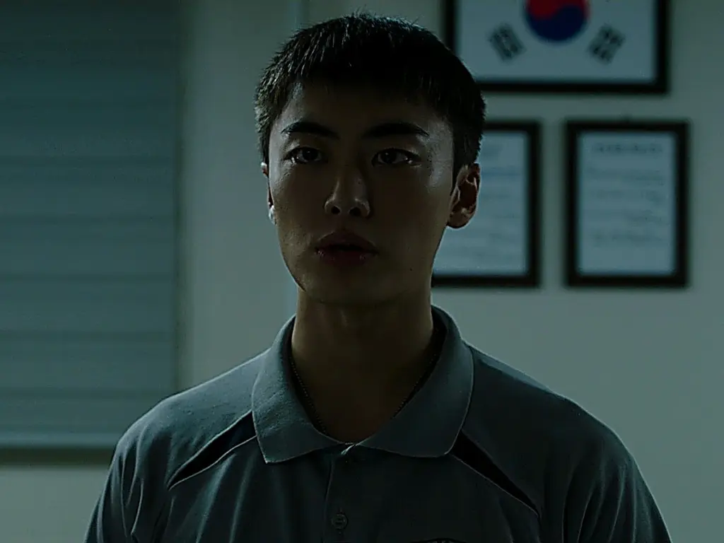 Kim Hyun-wook facing off against Park Min-seok in a dimly lit barracks corridor
