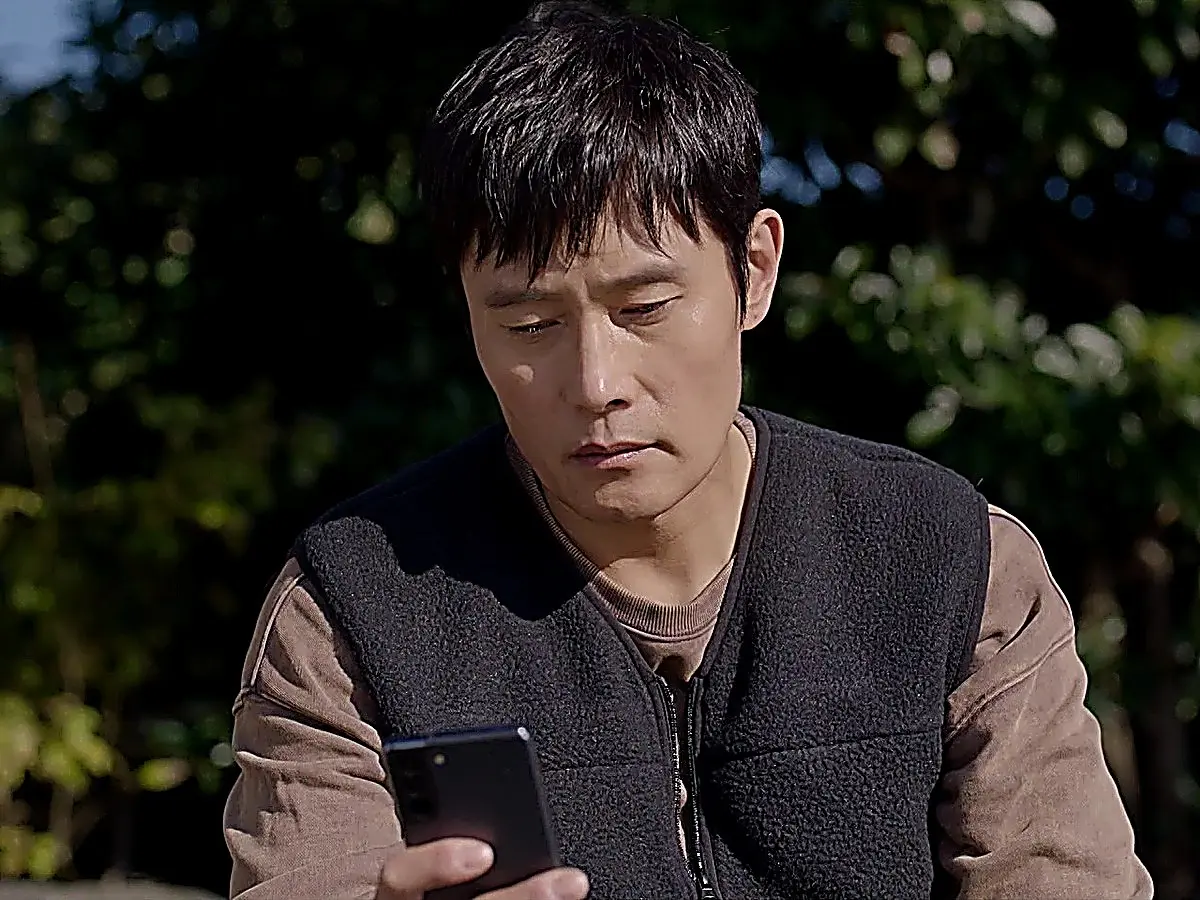 Lee Dong-seok sitting in his truck wearing a fleece vest over a crewneck sweatshirt