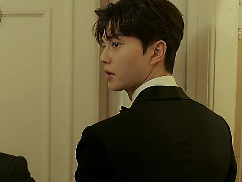 Kang Bi-o wearing a tailored black formal tuxedo jacket with a white dress shirt and black bow tie