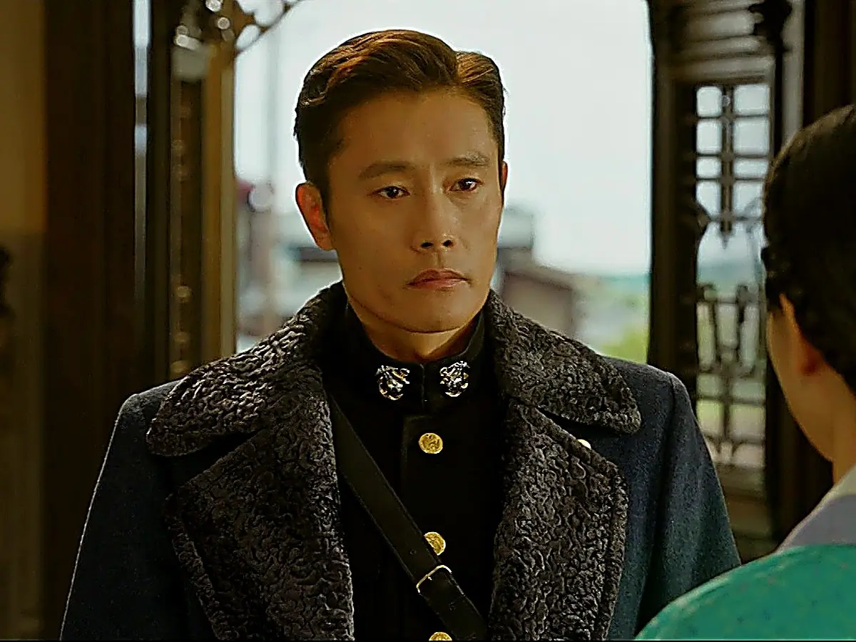 Eugene Choi wearing a dark wool coat with wide textured shearling lapels over a standing-collar uniform