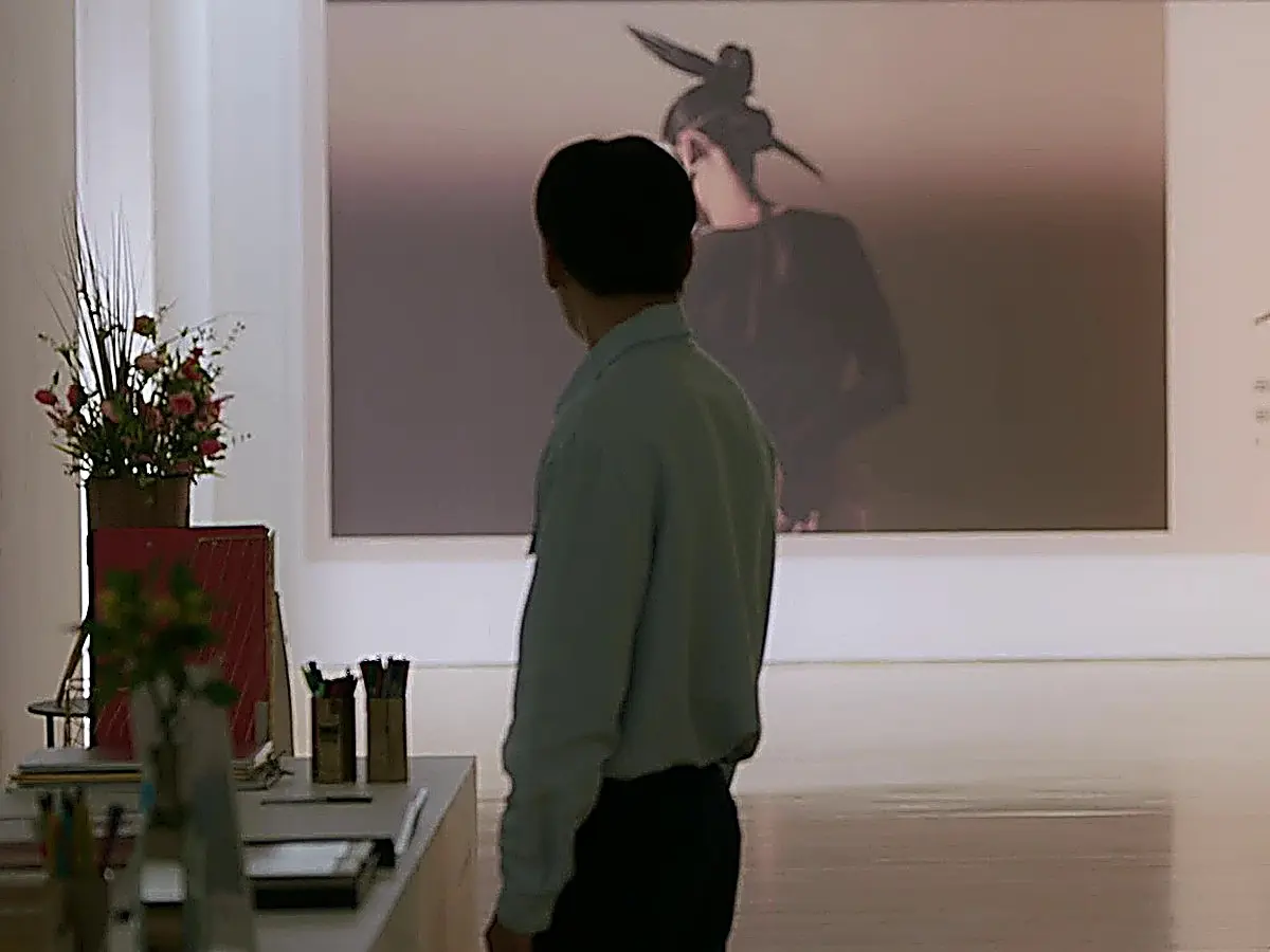 Cho Yong-pil viewed from behind wearing a light collared shirt and dark trousers at an exhibition