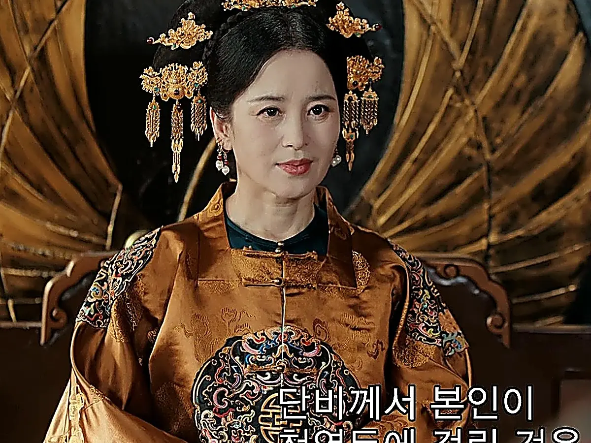 Empress Dowager wearing a copper-toned silk court robe featuring a circular embroidered crest and layered gold headdress