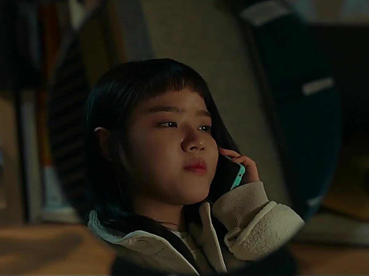 A young woman holding a mobile phone to her ear reflected in a round mirror