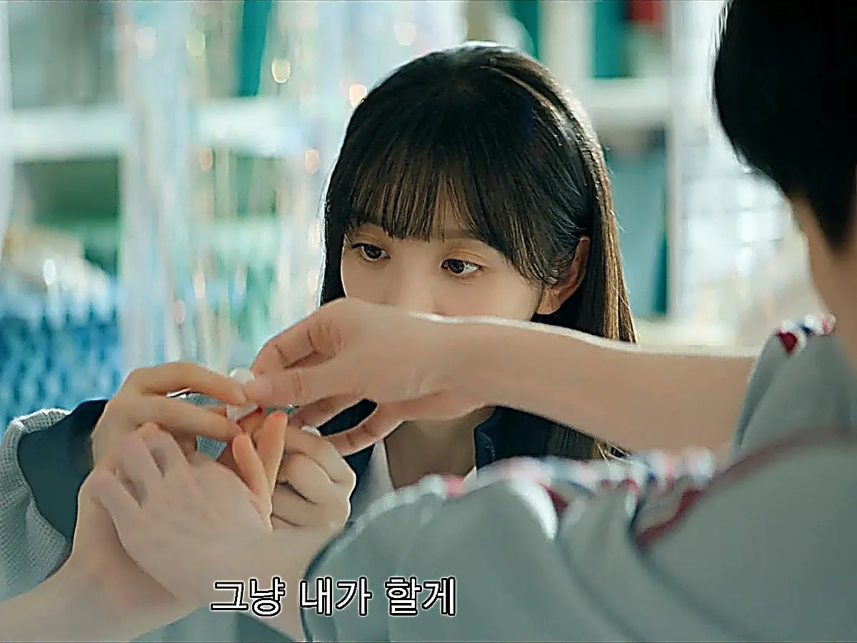 Two pairs of hands applying a small adhesive bandage to a finger while a person watches