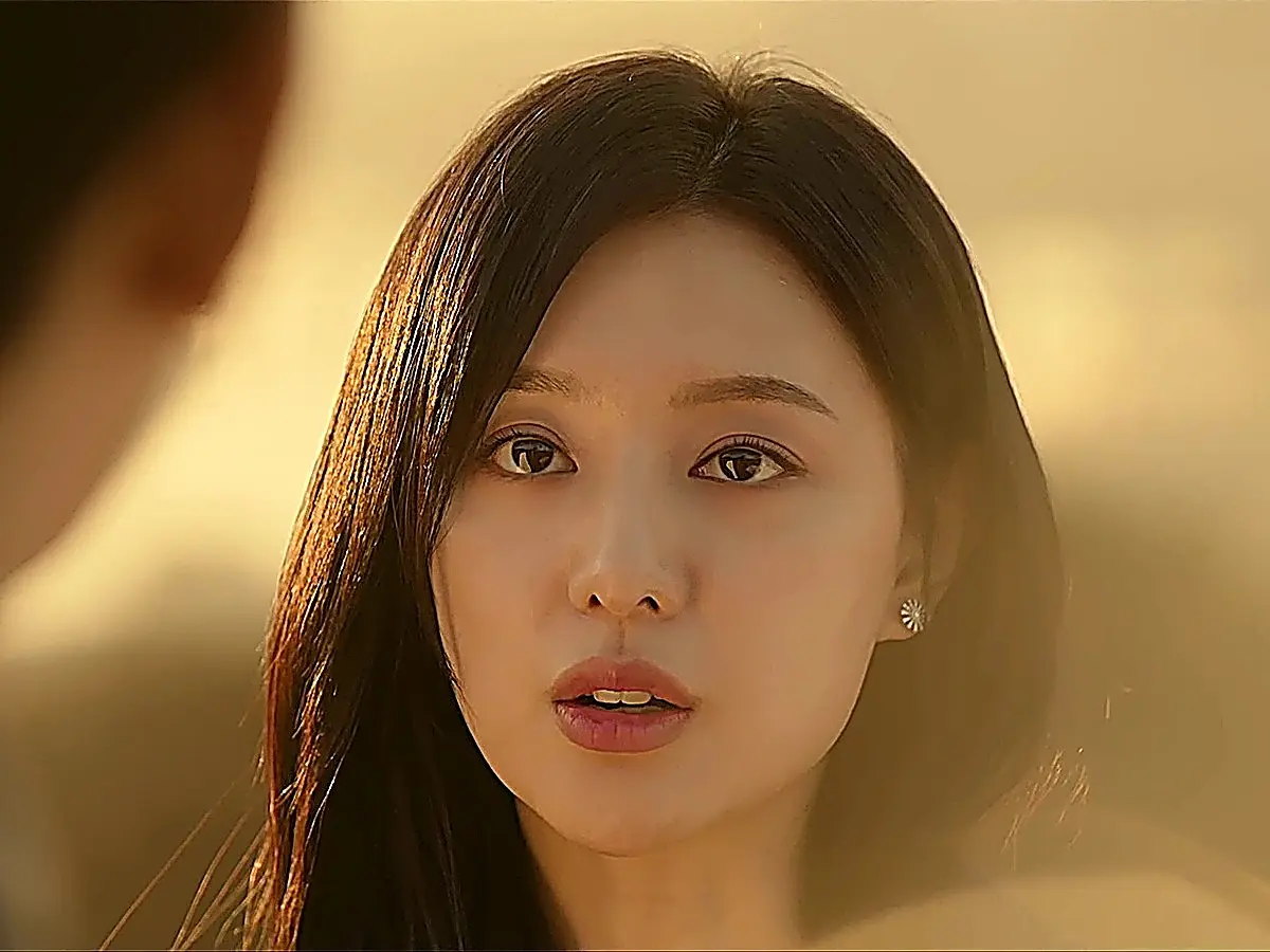 Woman with dark hair and floral earrings gazing forward in golden sunset light
