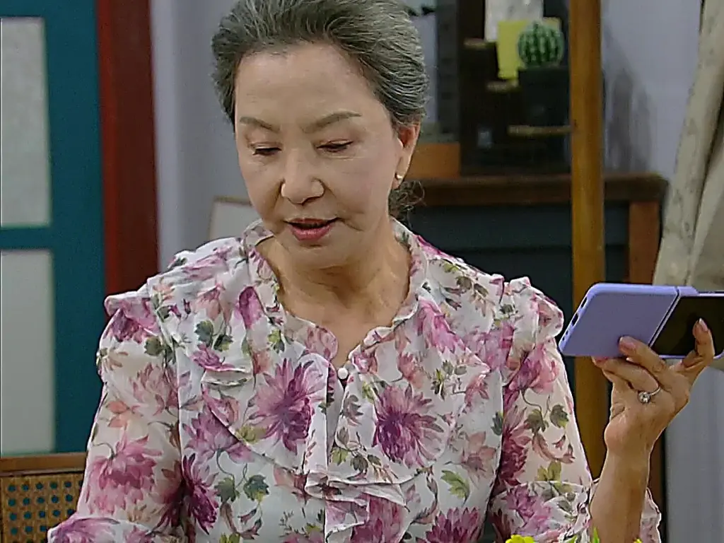 Wang Geum-ja inspecting photos confirming Joo Mi-ran's real identity in Trap of Desire Episode 29
