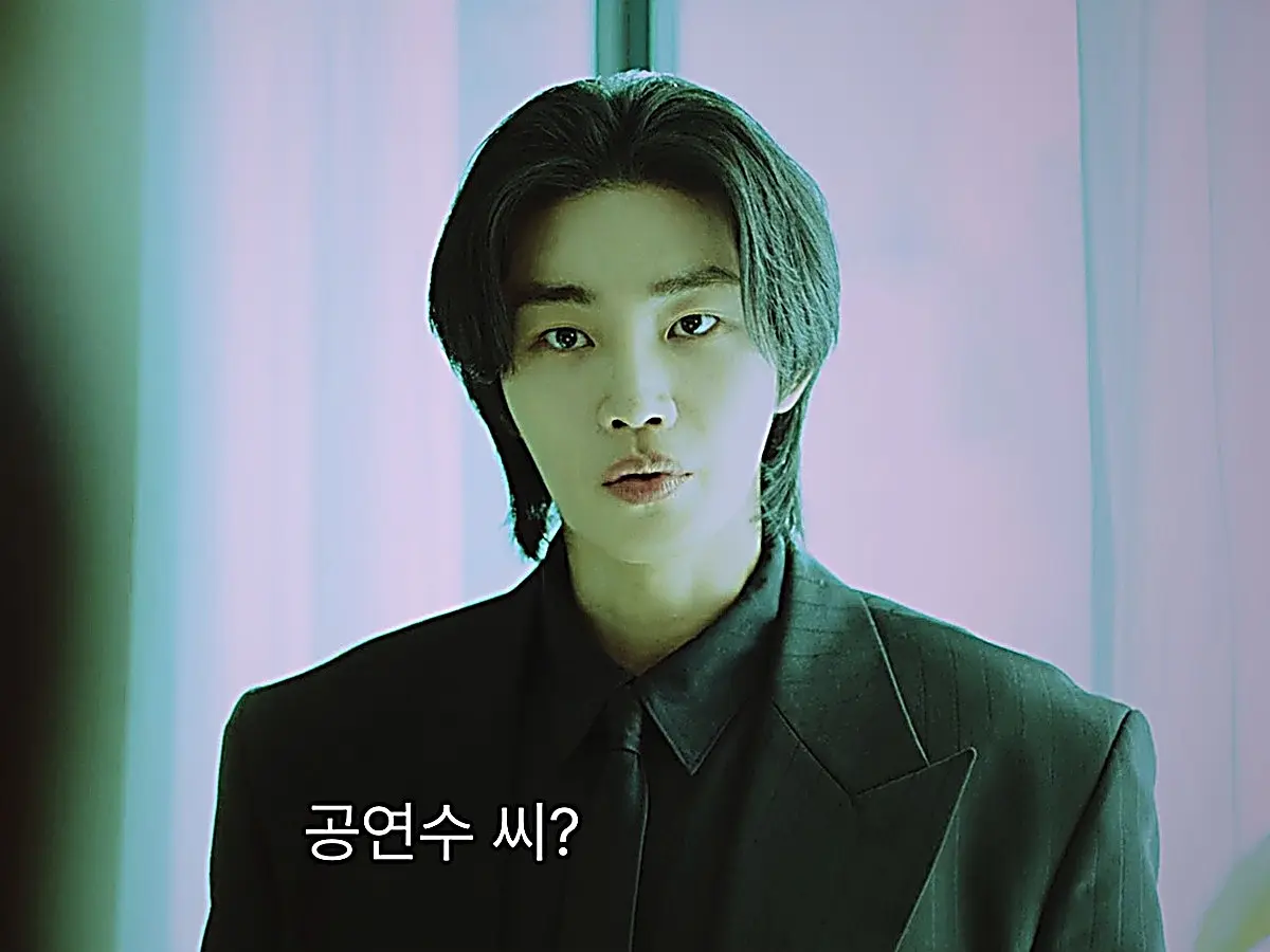 Dokgo Dal wearing a dark tailored business suit in a meeting room