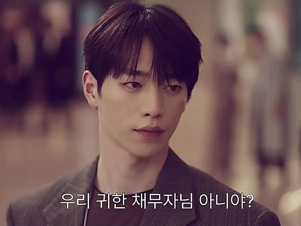 Namgung Ho in a tailored grey textured blazer layered over a dark top