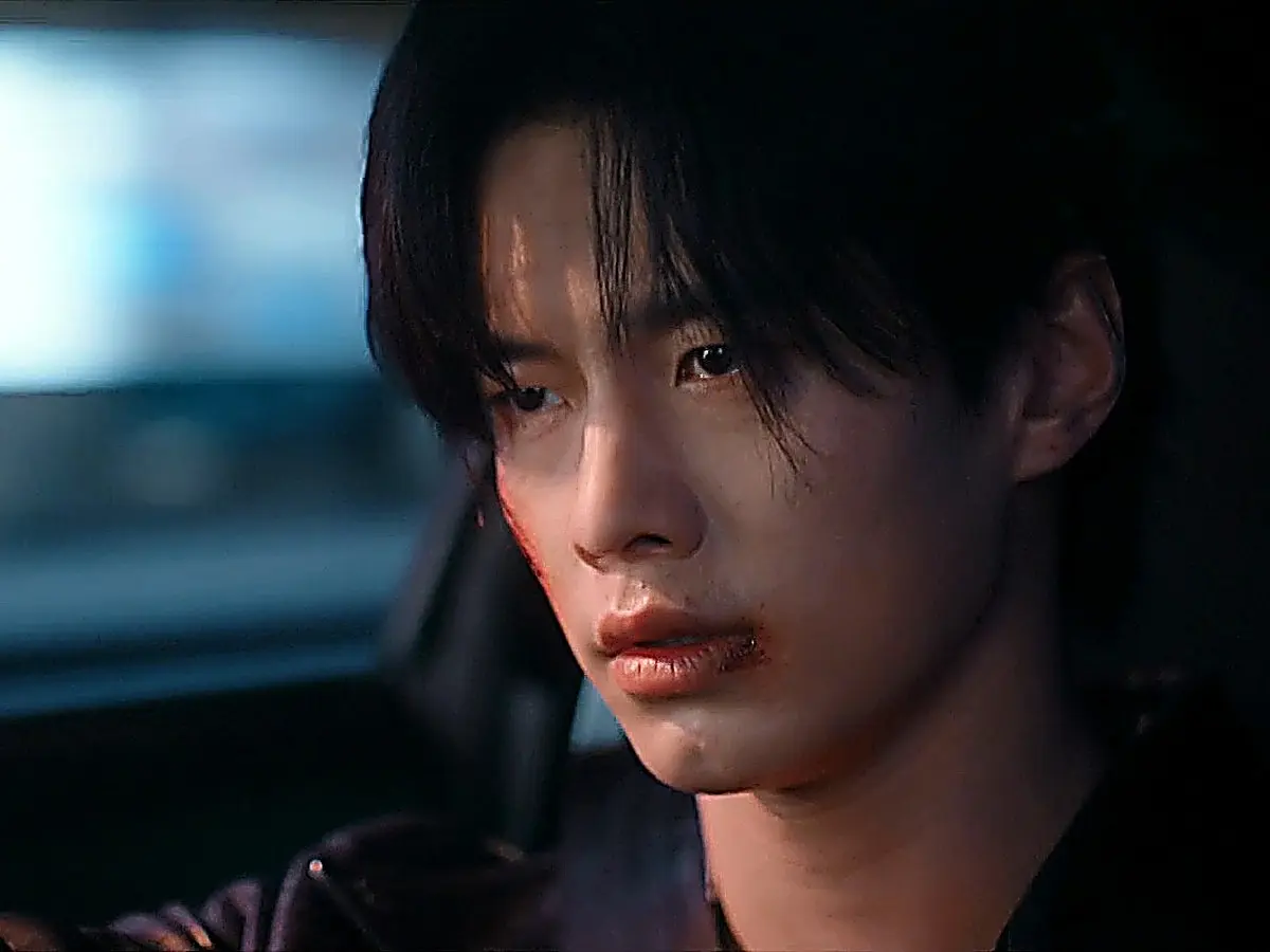 Jin Zhao in a black moto leather jacket behind the steering wheel