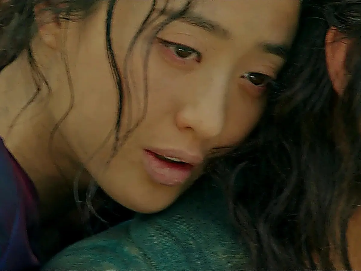 A woman resting her head against someone's shoulder with a pale expression