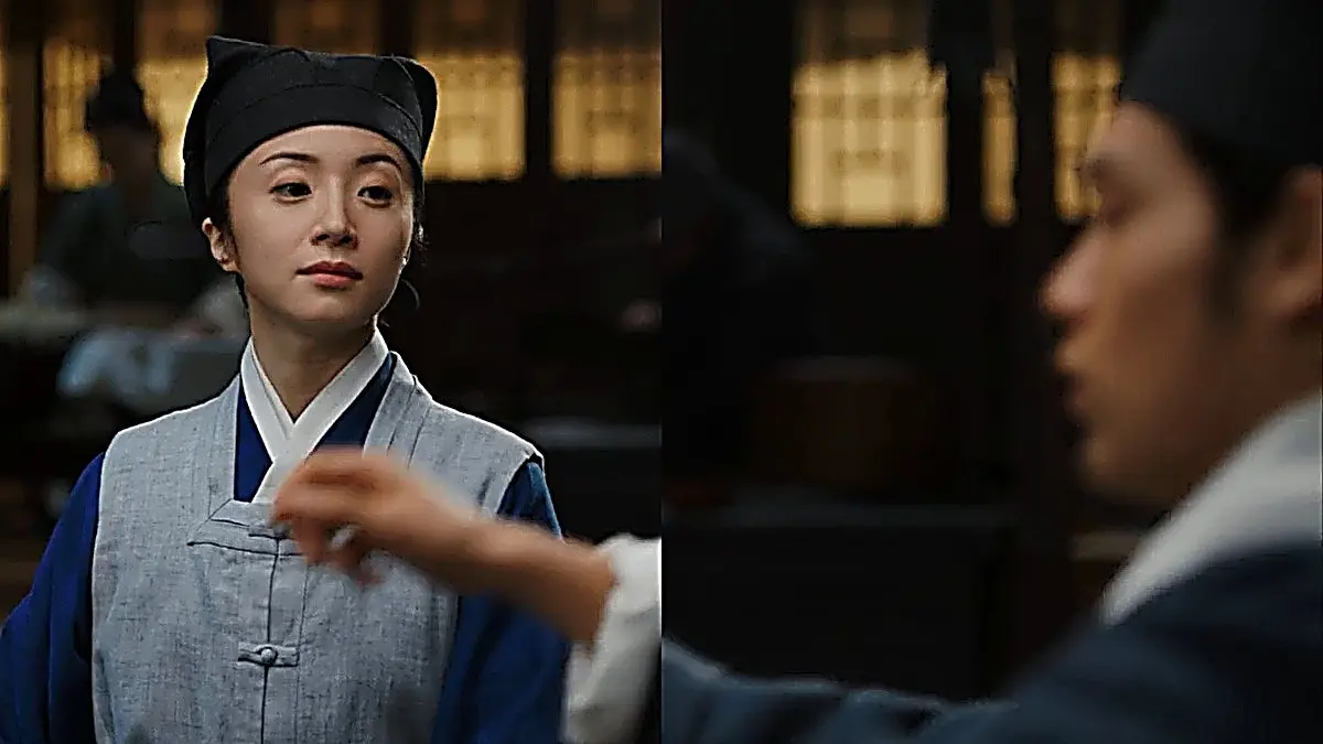 Luo Su wearing a blue inner robe, slate grey sleeveless vest with frog fastenings, and a black cloth headwrap