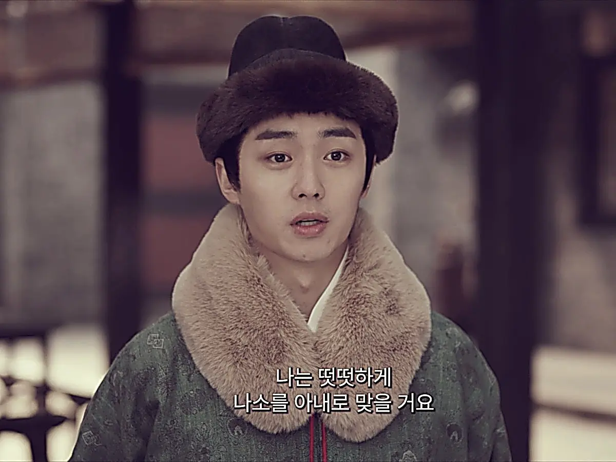 Qi Menglin in a green winter robe with plush tan fur collar and brimmed cap