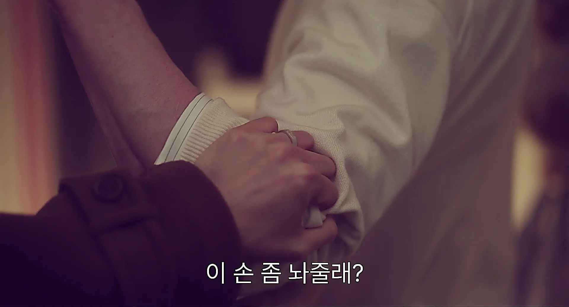 Close-up of a cream knit sleeve over a collared shirt held by a hand in dark outerwear
