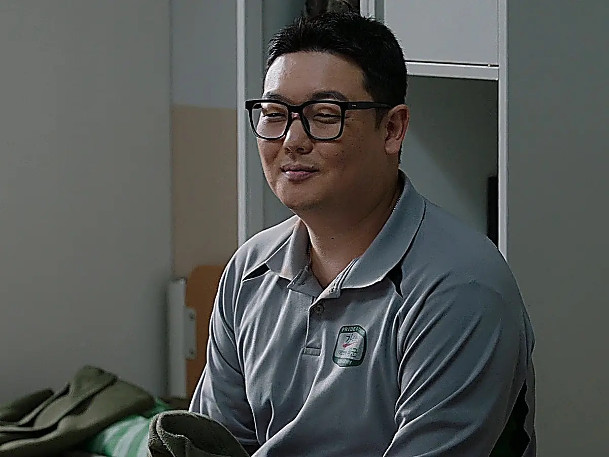 Park Min-seok wearing the loose-fitting grey athletic polo shirt with a chest patch