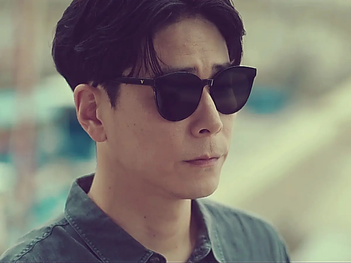 Namgung Ho outdoors wearing dark sunglasses and a grey collared shirt