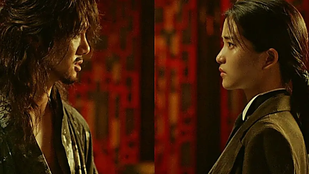 Go Ae-shin wearing a dark tailored blazer and white collared shirt in profile beside Gu Dong-mae in a textured dark robe