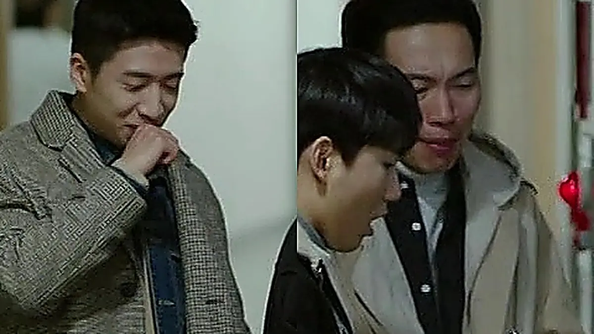 Park Kwang-beom wearing a grey houndstooth overcoat layered over a blue collared shirt alongside Company Five soldiers in a hospital corridor