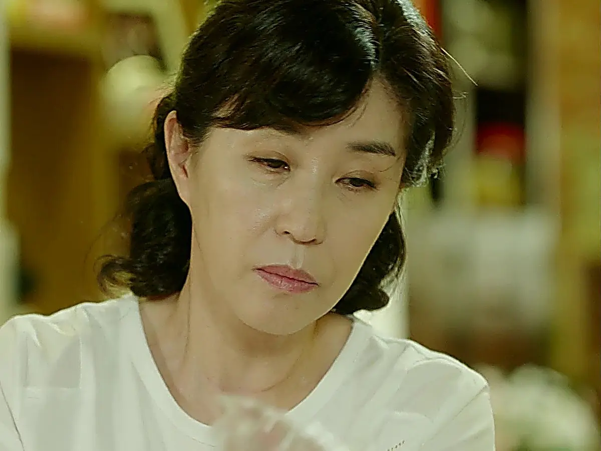Close-up of a woman looking downward wearing a white t-shirt