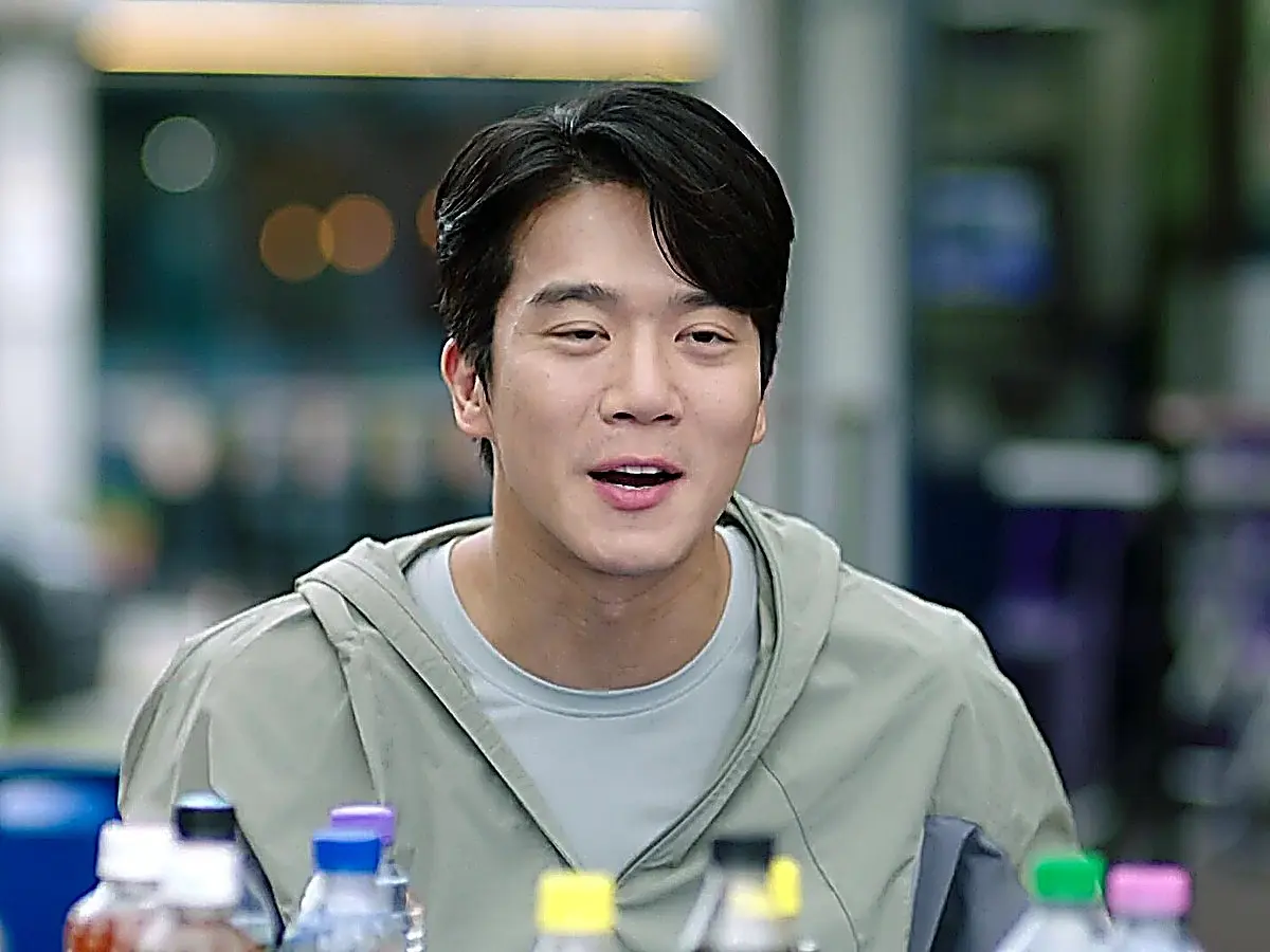 Kim Mu-jin wearing a pale sage green zip-up hoodie over a crewneck tee