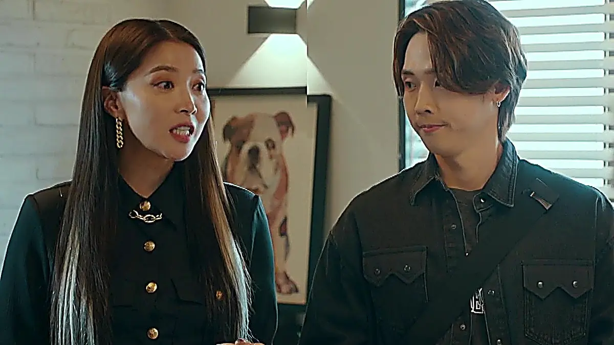 Michelle in a dark collared button-down shirt standing beside Moo-yeol in a dark denim overshirt
