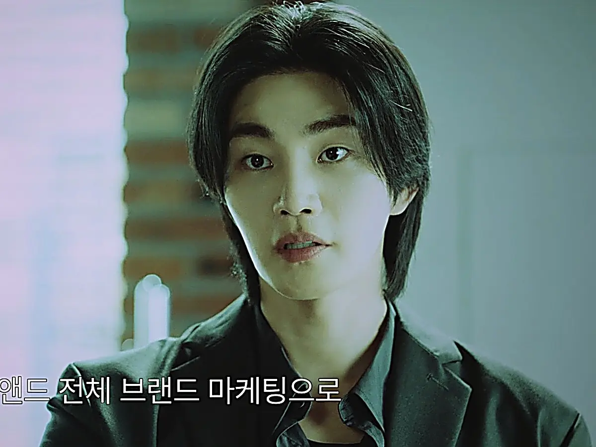 Dokgo Dal wearing a dark tailored blazer in the agency conference room